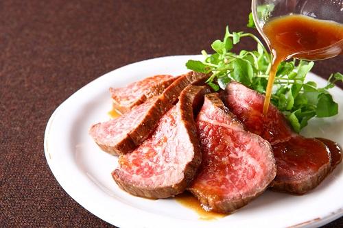 スライスした和牛のローストビーフにローストビーフソースをかけている