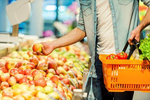 スーパーでりんごを選ぶ男性