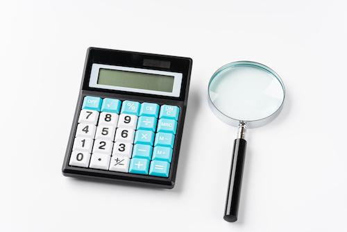 査定をイメージした虫眼鏡と電卓の写真