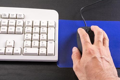 マウスパッドの上でマウスを操作している人の手の写真