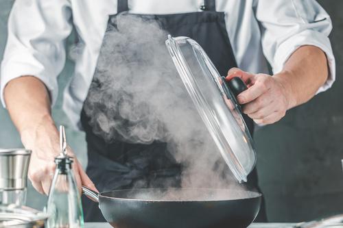 フライパンで調理をする男性の画像