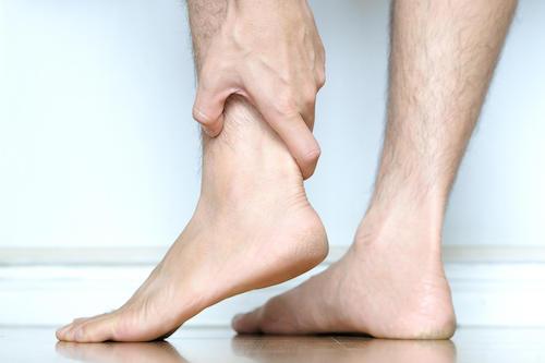 手で足首を押さえる男性の写真