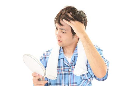 鏡を見ながら前髪を気にする男性の写真