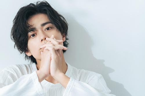 今風のパーマがかったセンターパートスタイルの若い男性の画像