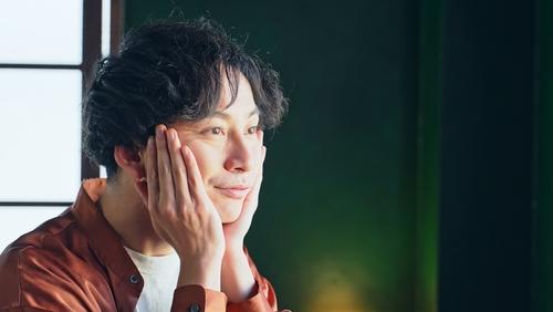 頬に手を当てて一点を見つめる男性の写真